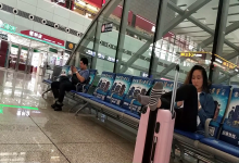 Girl put her feet on the trolley case when waiting for the train in railway station lounge