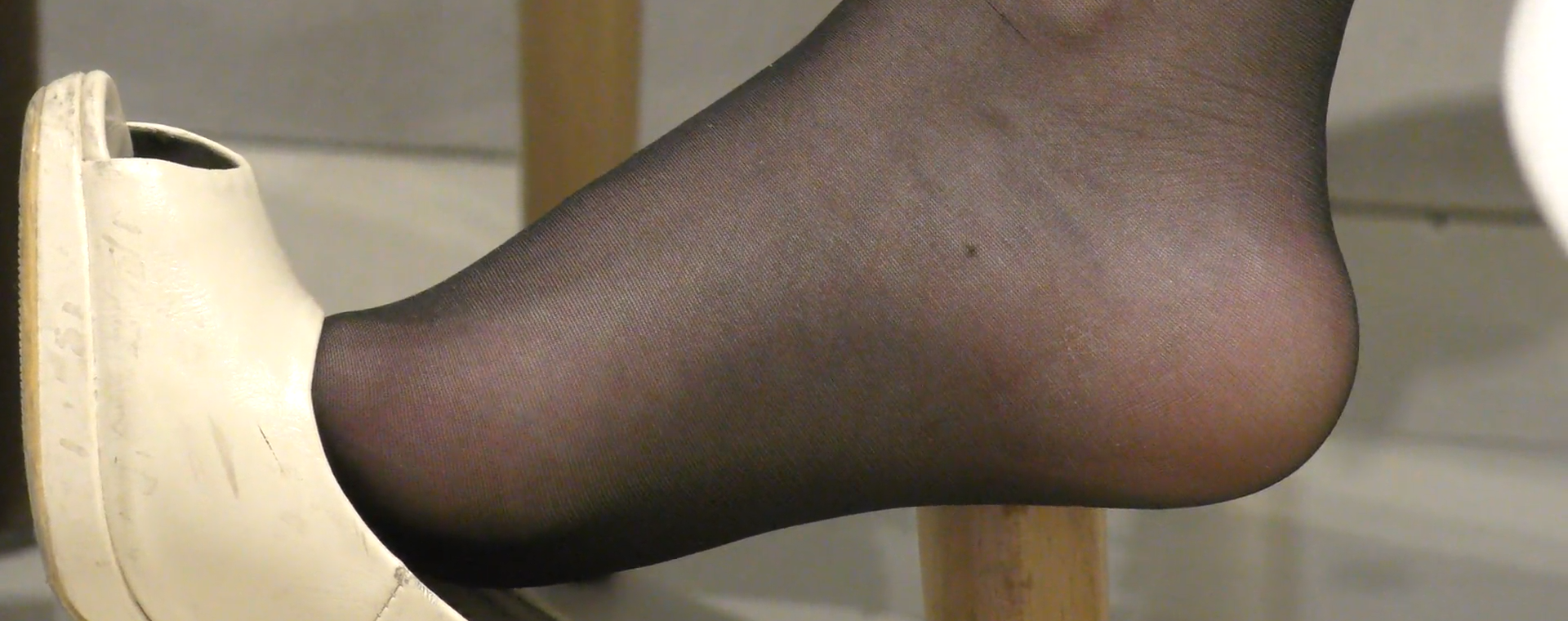 Close to her dangling black nylon feet 