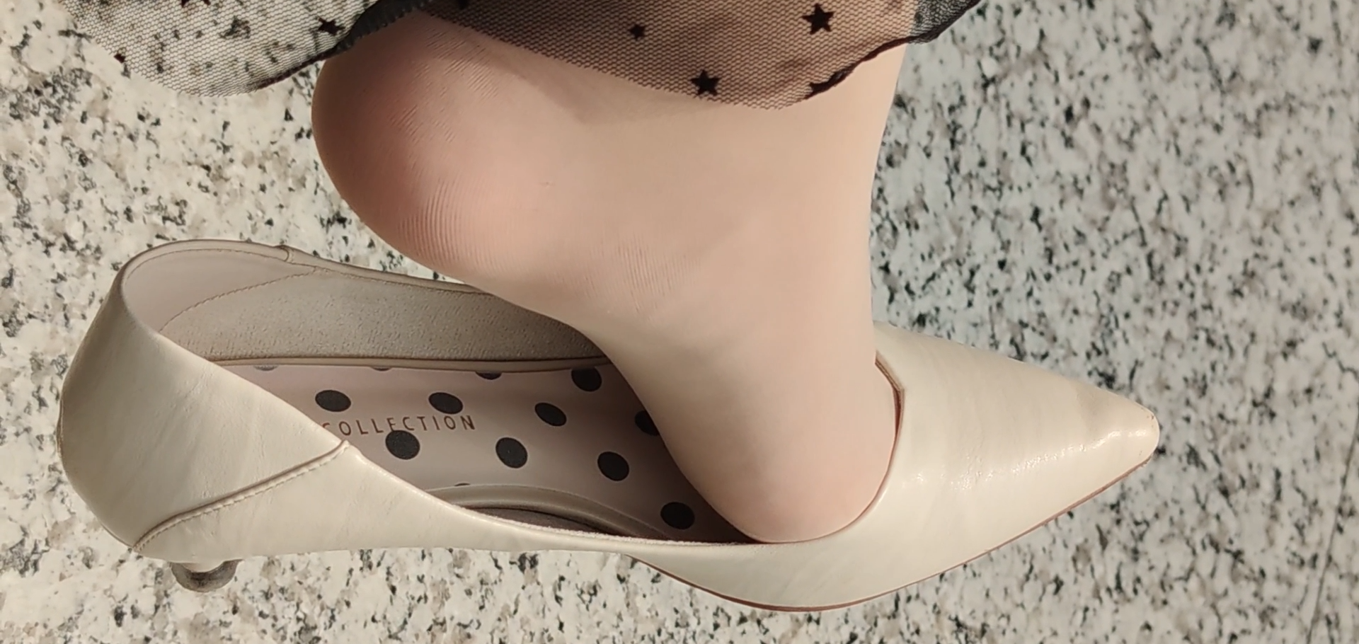 Lady dangling shoeplay in white heels ,we can see the brand of her heels